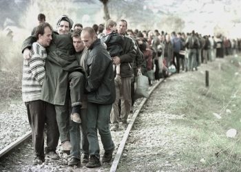 “After we had walked for hours on end, exhausted and overwhelmed, the Serbian forces stopped us at the train station in Prishtina, where we sat down on the ground, and they began to…”